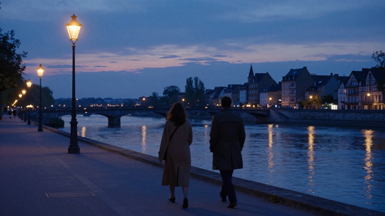 Two figures walking side by side along the Loire River at dusk, backlit by soft streetlights.